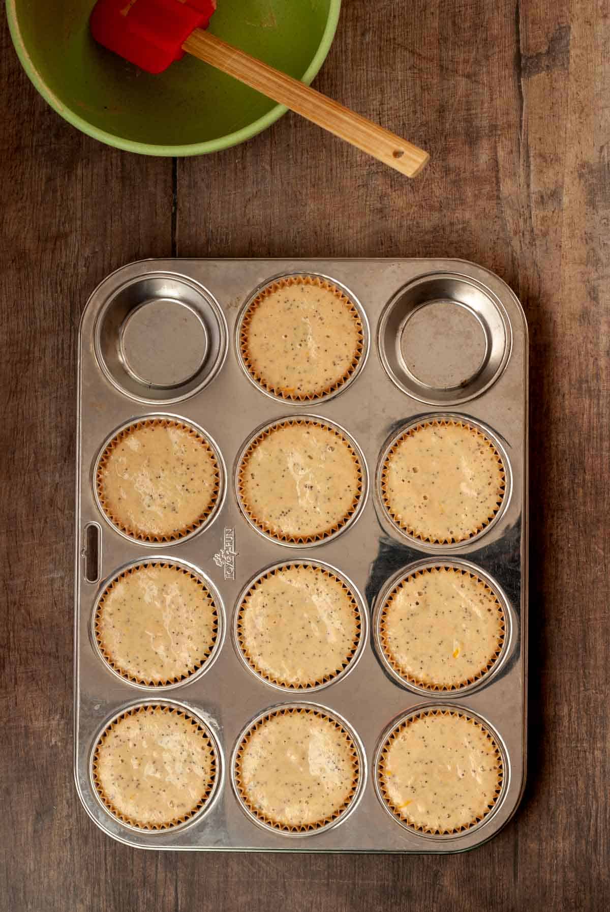 Muffin tin filled with batter and the empty batter bowl behind it.