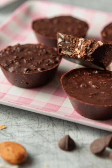 Five small handheld chocolate dessert cups on a plate.