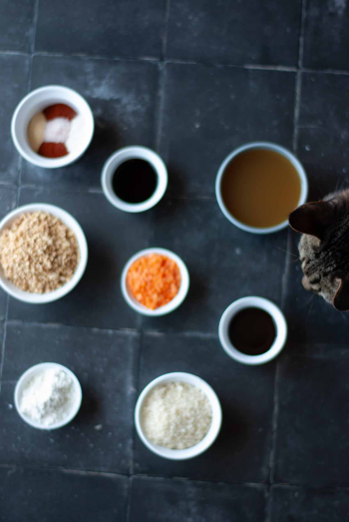 Small bowls of ingredients for recipe with Charlie the Cat sneaking into the picture being curious.