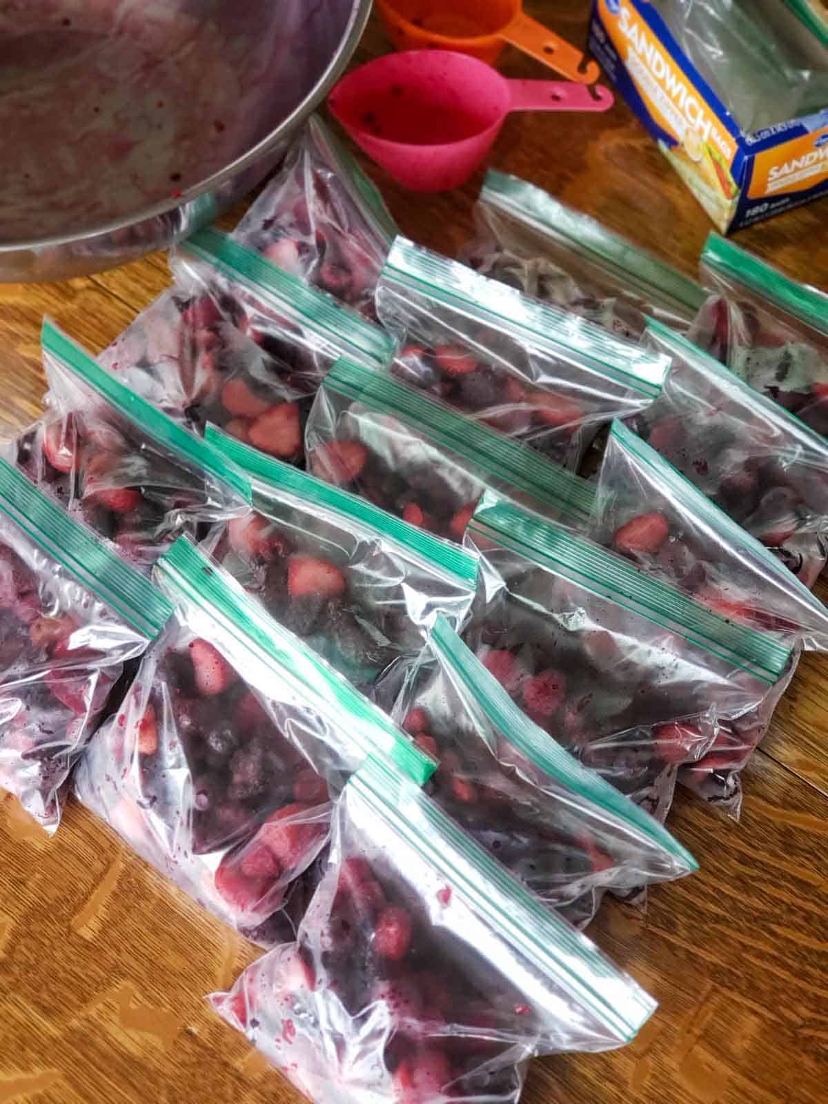 The finished bags of berries on the table with and orange and pink measuring cup in the background.
