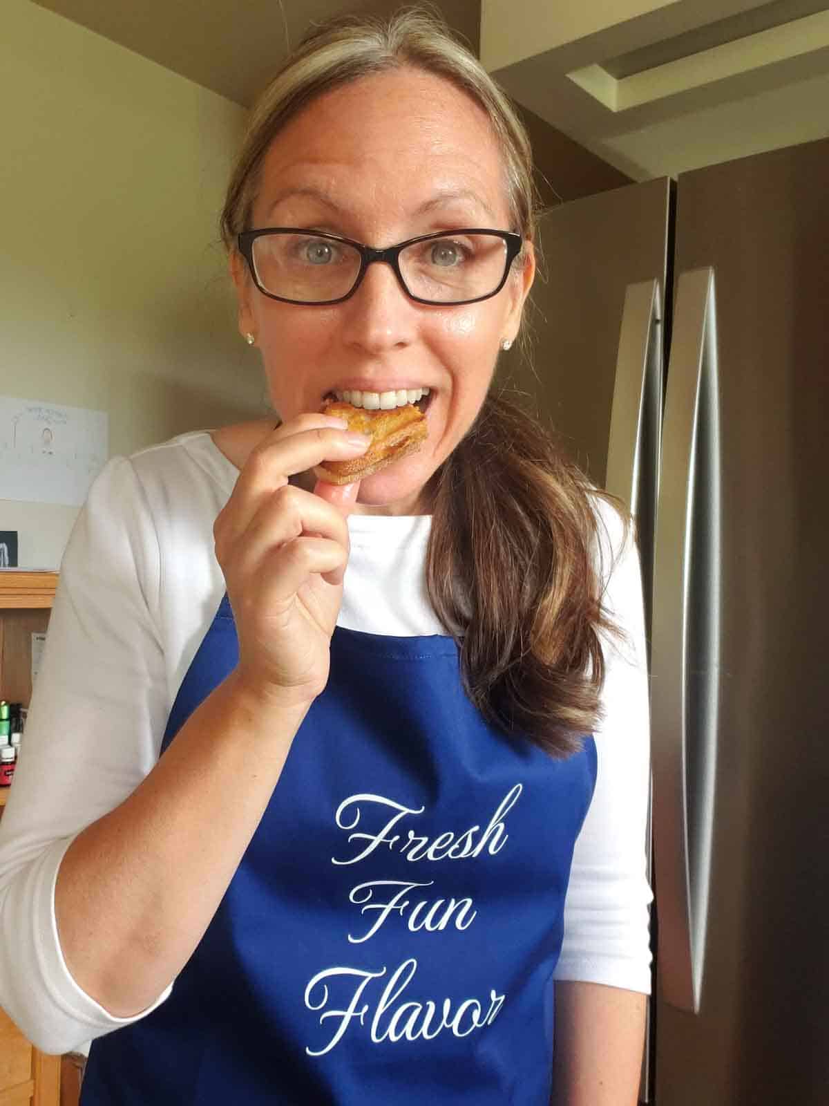 Rhonda in a blue apron enthusiastically taking a bite out of one of the grilled sunbutter sanwiches.