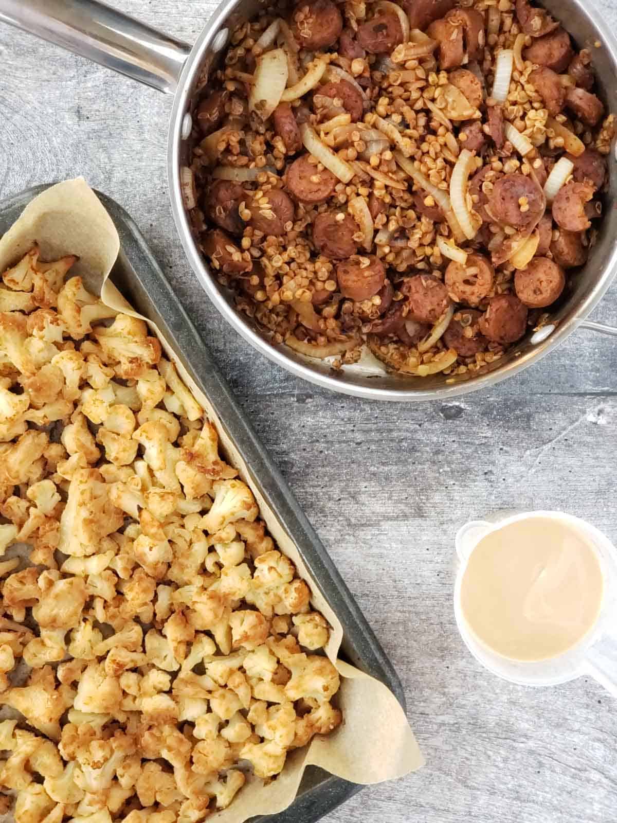 A pan of balsamic glazed caramelized onions, lentils, and vegan sausage. A pan of roasted cauliflower, and a cup of lemon tahini sauce.