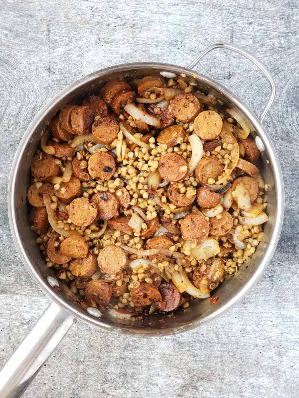 A pan of cooked vegan sausage, lentils, and caramelized onions coated in a balsamic vinegar reduction.