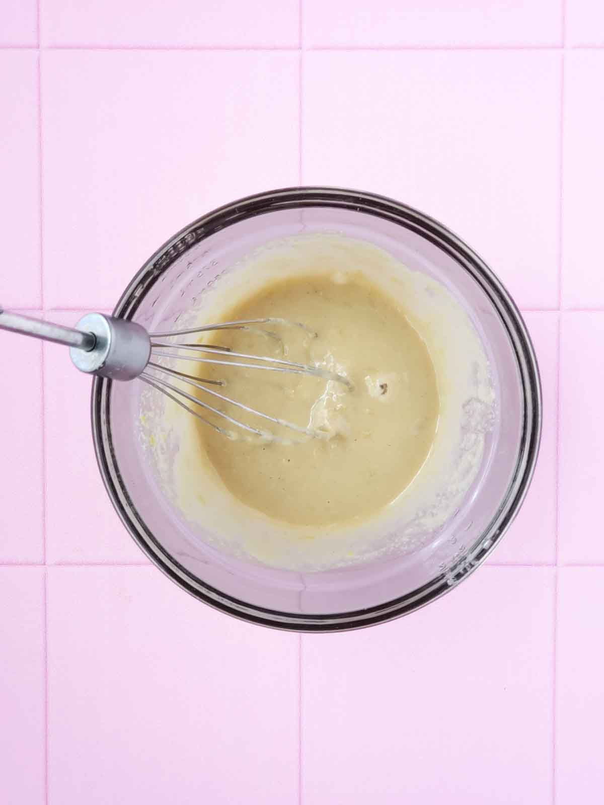 A mixing bowl showing all wet cookie ingredients being whisked together to combine.