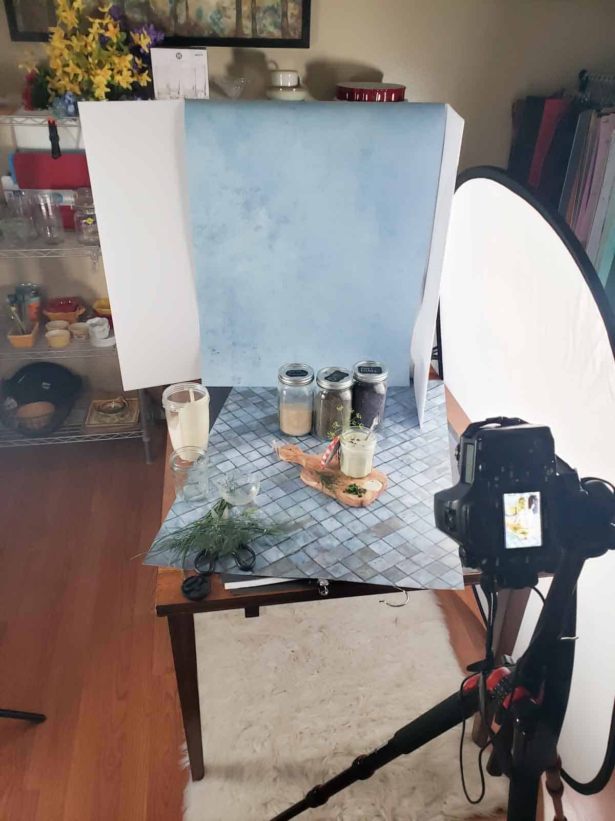 Setting up the scene, camera, and lighting for the Ranch Dressing photo on a blue tile flat lay with spices in the background.
