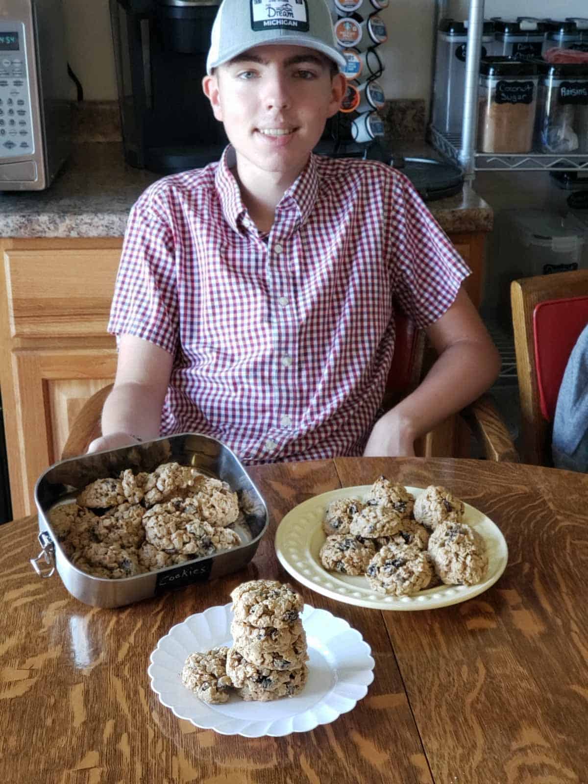 Justin smiling at table with fresh oatmeal raisin cookies on plates.