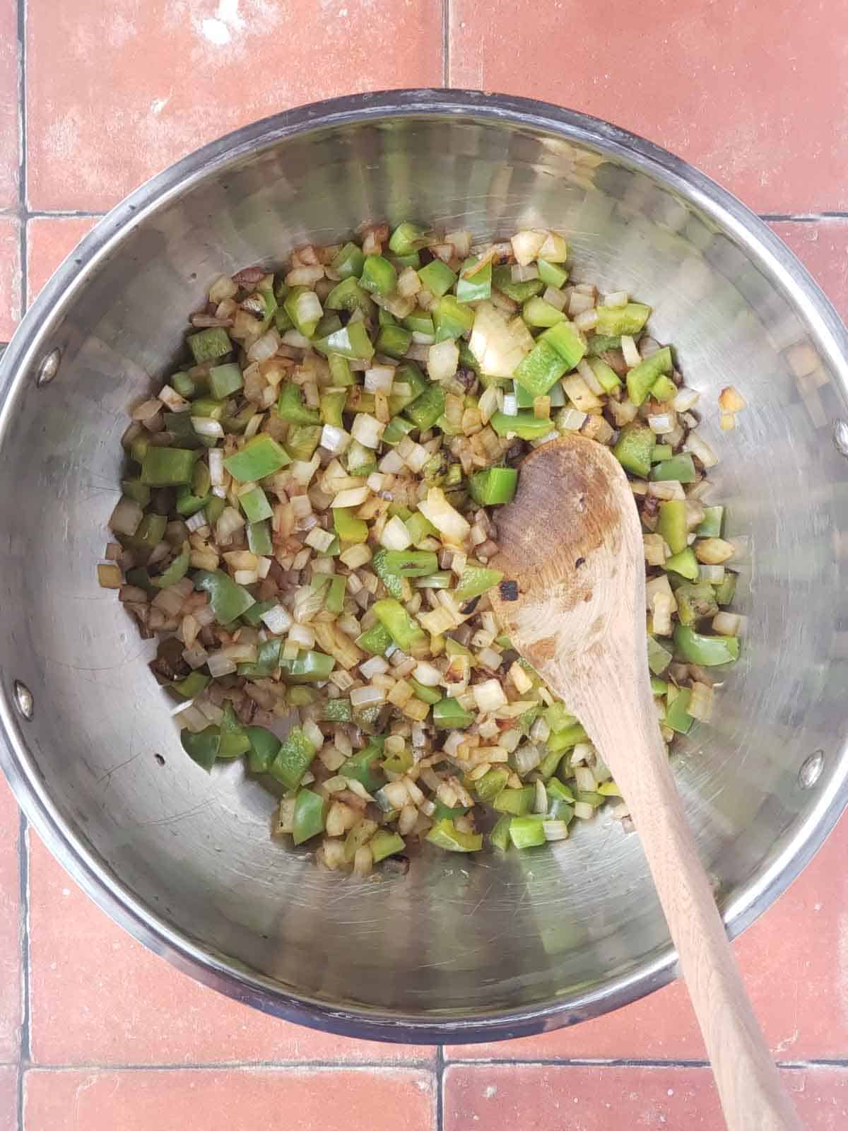 Sautéed onion and green bell pepper cooking in a pot.