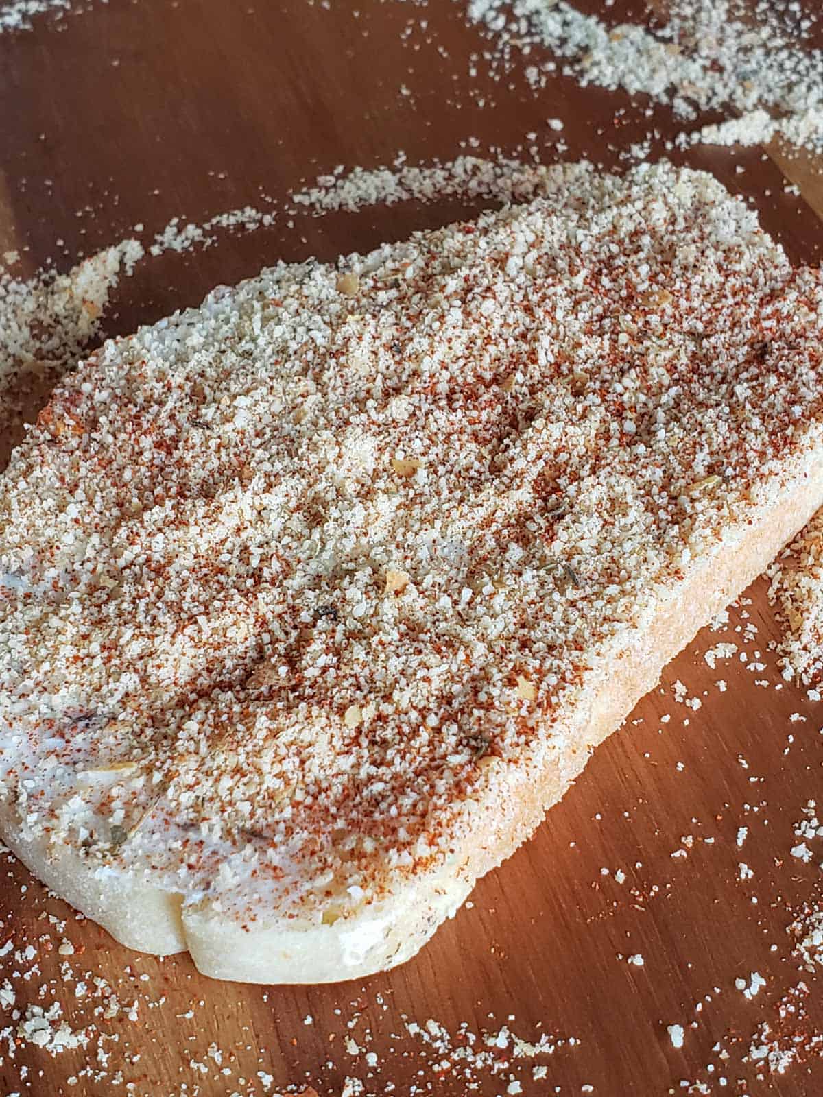 Close-up of a single sourdough slice spread with the seasoned butter and topped with parmesan and paprika.
