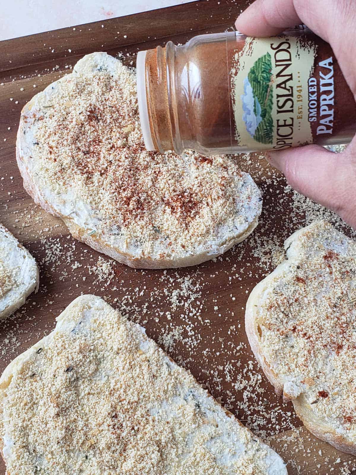 Hand sprinkling smoked paprika over buttered sourdough slices for color.