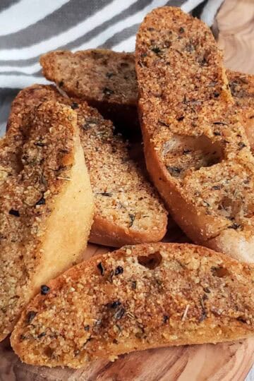 Homemade vegan garlic toast served on a wooden board, crispy and golden brown.