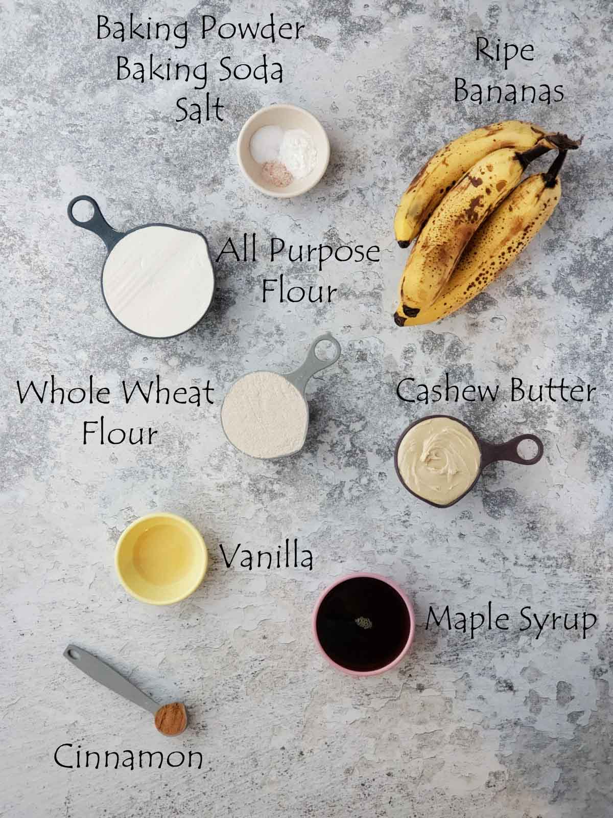 Overhead view of labeled ingredients for vegan banana bread on a textured surface.