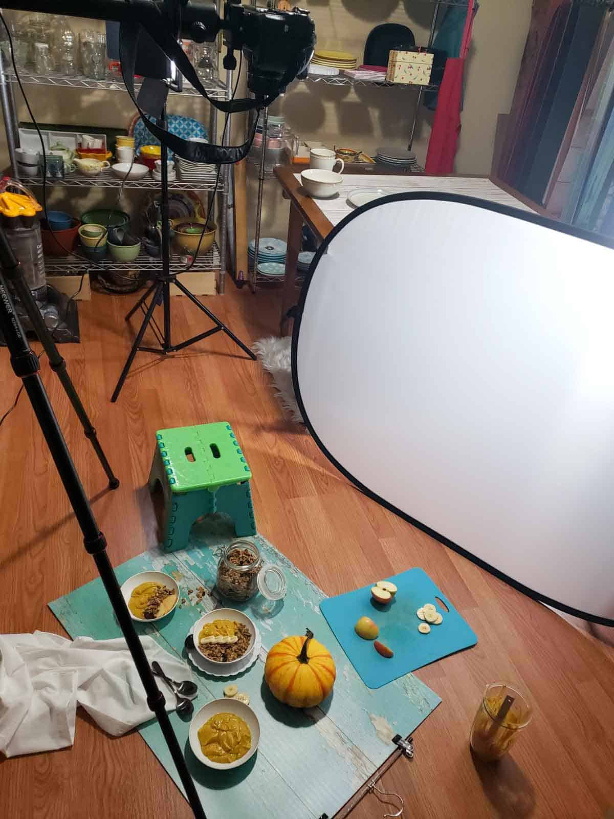 Behind-the-scenes photo setup for styling vegan pumpkin breakfast bowl with lights, props, and pumpkin.