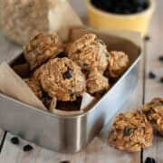 Chewy blueberry oat sunbutter balls arranged in a metal container with parchment paper.