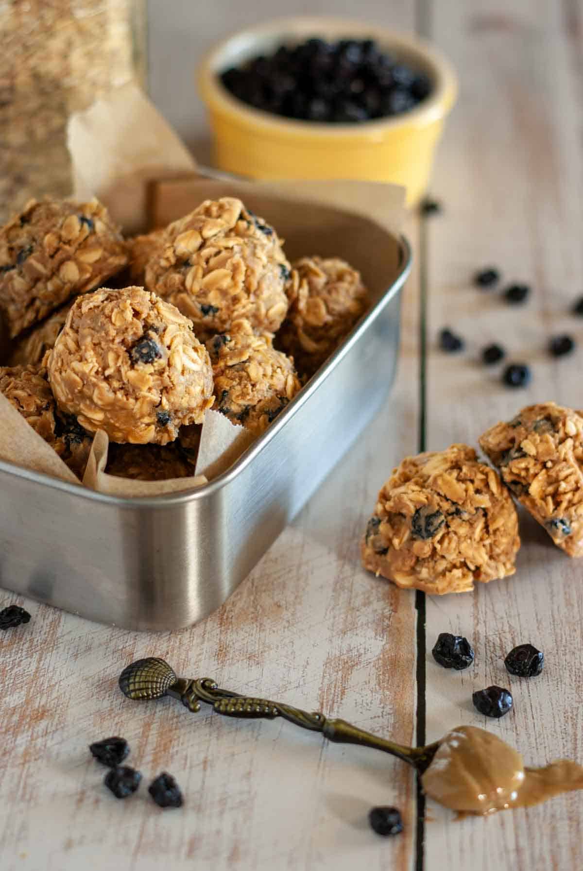 Chewy sunbutter blueberry energy balls arranged in a metal container with parchment paper.