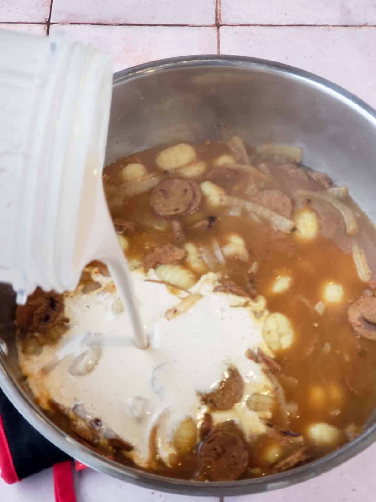 Pouring creamy cashew sauce into the pot.