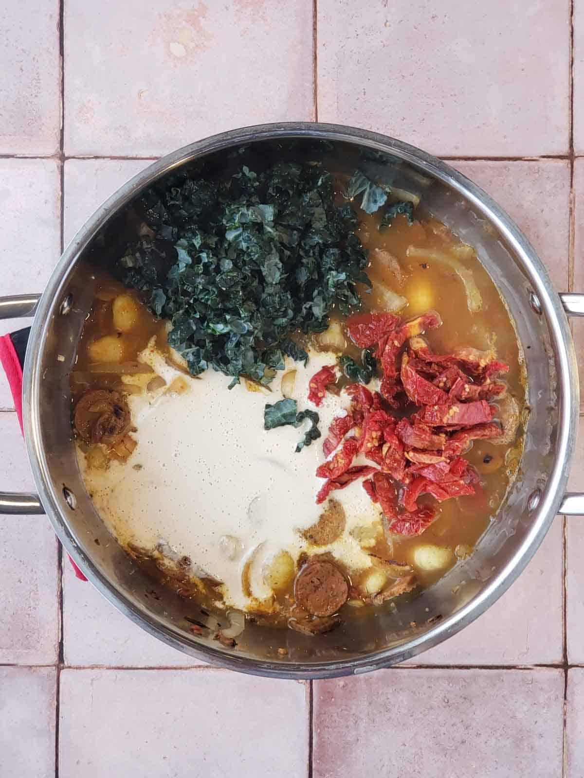 Adding chopped kale and sliced sun-dried tomatoes to the pot.