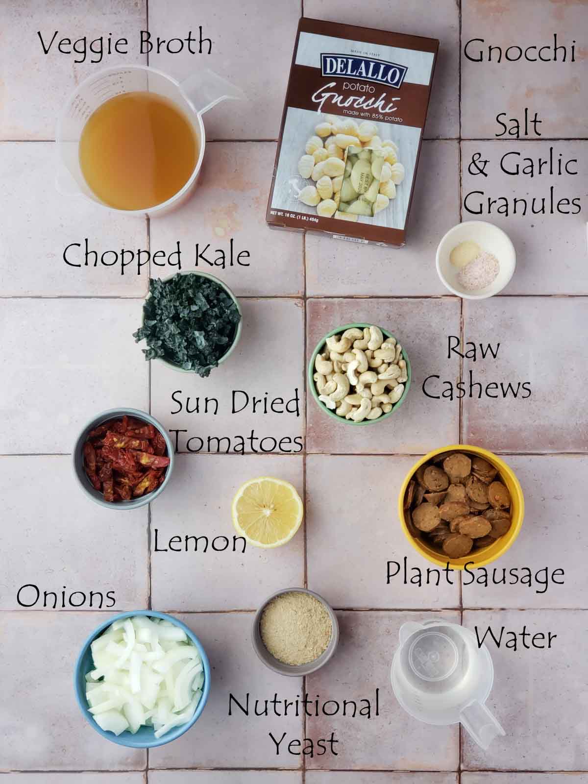 Overhead view of labeled vegan gnocchi ingredients including cashews, kale, sun-dried tomatoes.