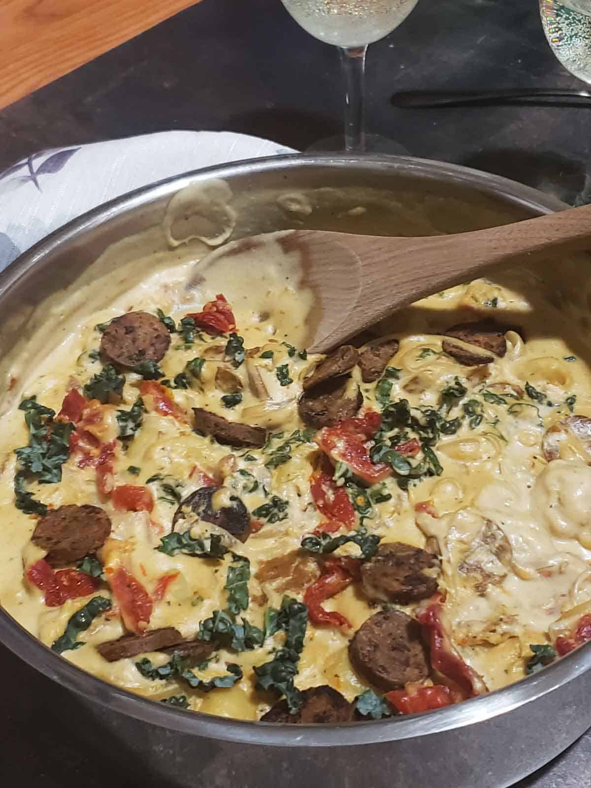 Close-up of creamy Tuscan vegan gnocchi with kale, sausage, and sun-dried tomatoes, ready to serve.