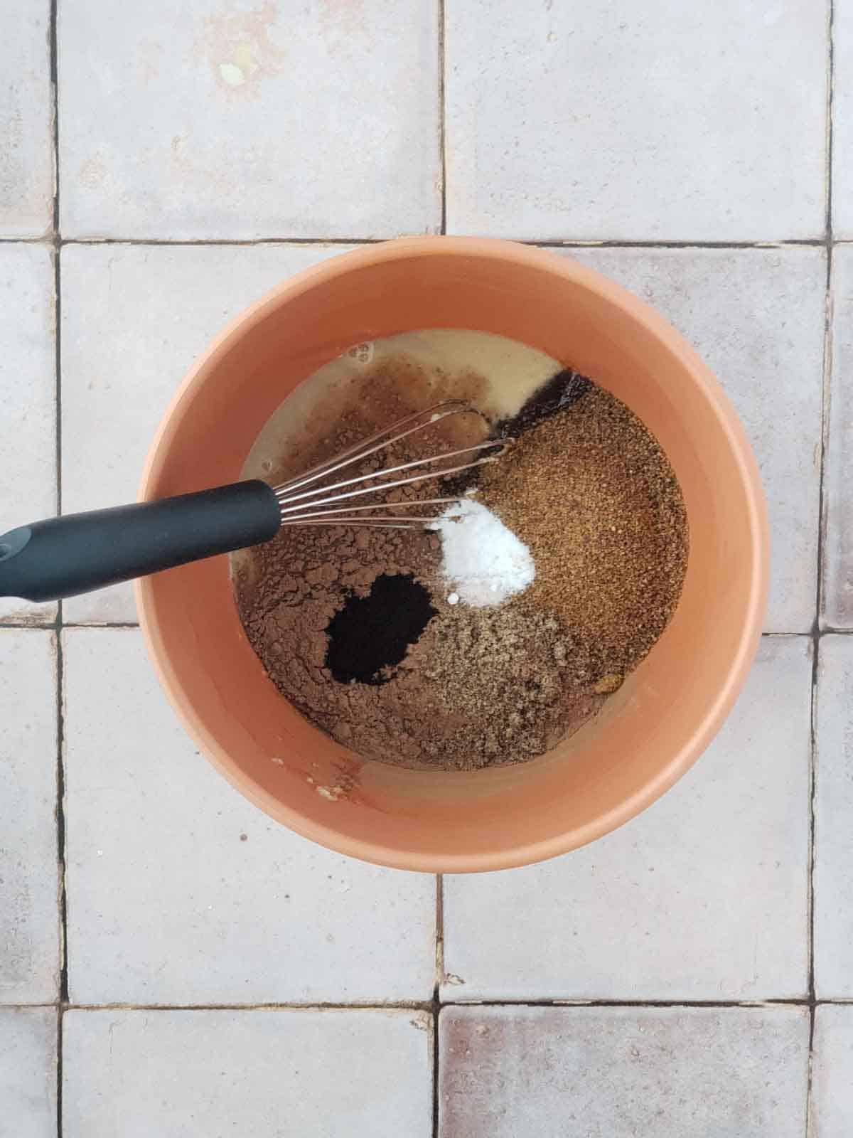 Adding coconut sugar cocoa powder flax espresso and salt to wet ingredients for chocolate marshmallow cookies.