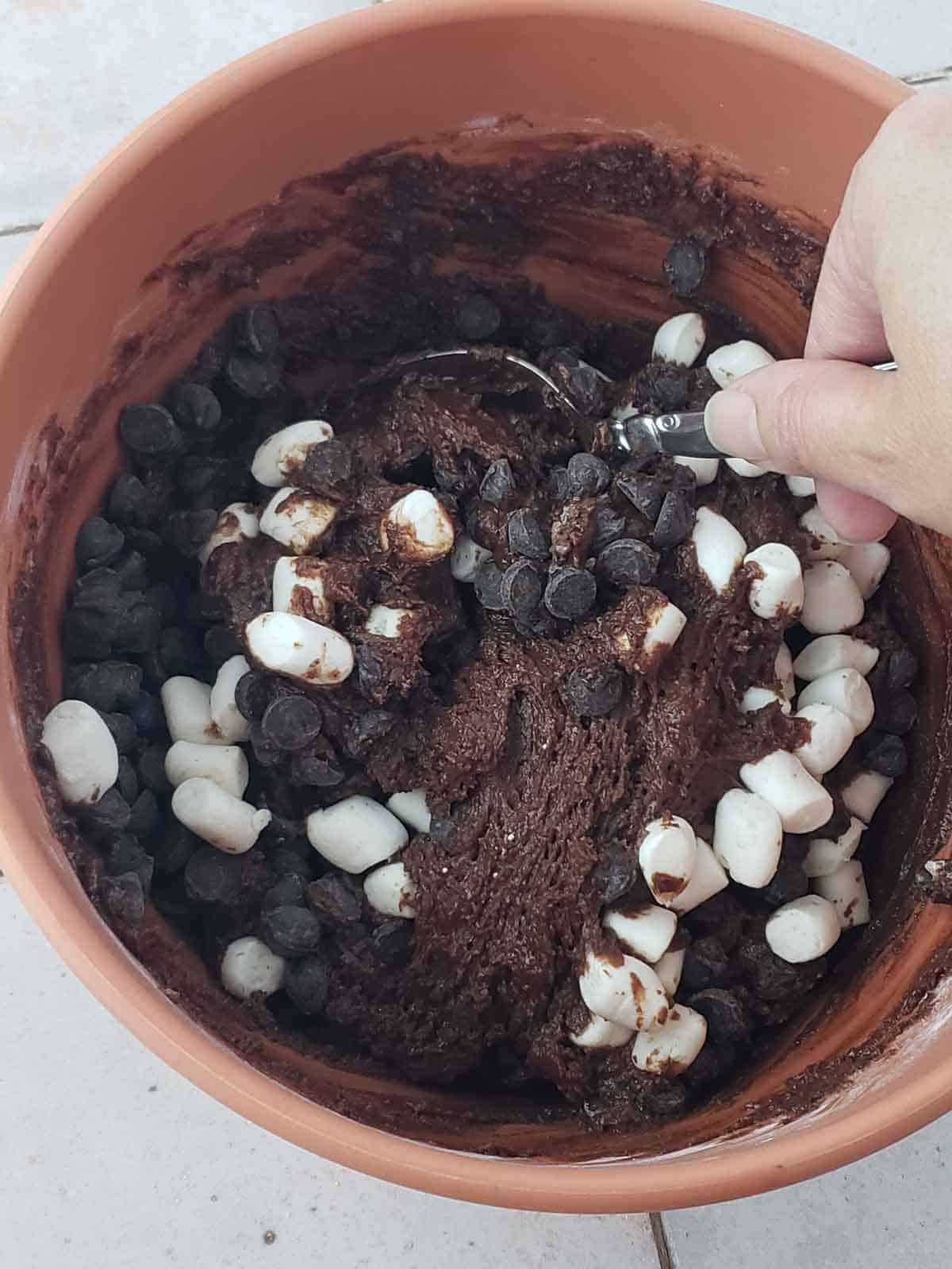 Stirring chocolate chips and marshmallows through thick fudgy vegan brownie cookie dough.