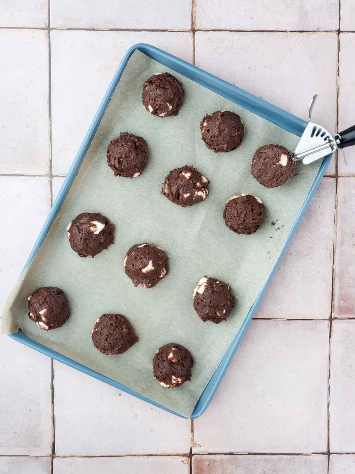 Cookie dough scoops on parchment-lined pan ready for the oven.