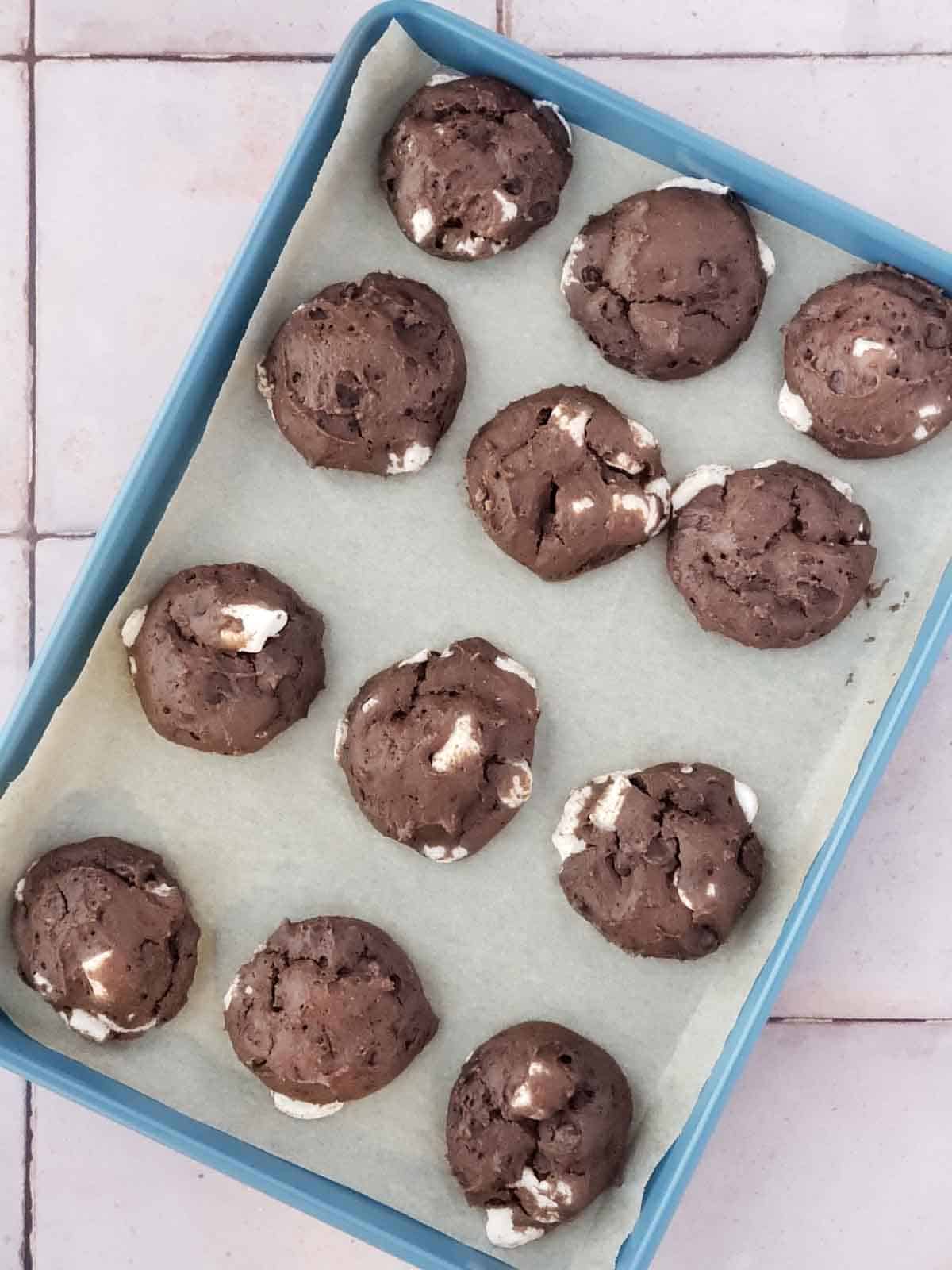 Freshly baked vegan brownie cookies with gooey marshmallow bits cooling on tray.