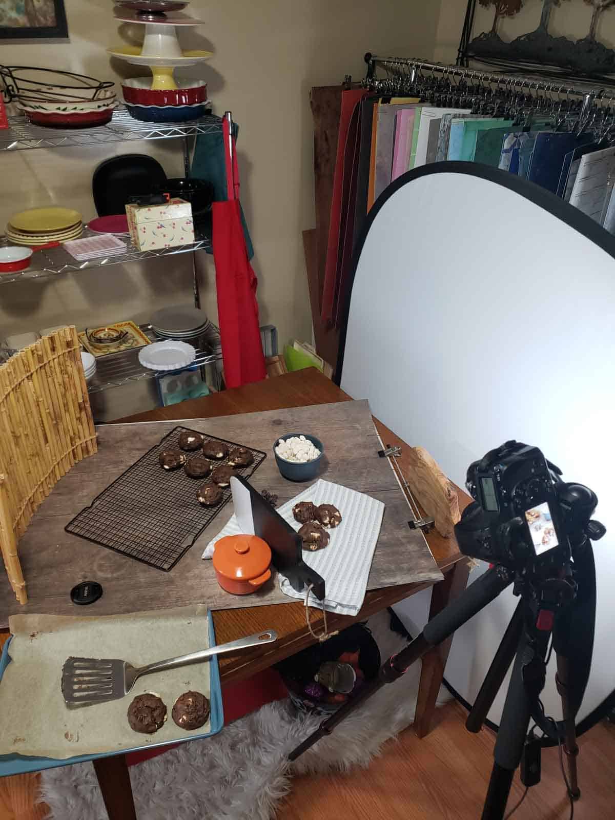 Behind-the-scenes cookie photography setup with props lights and cooling rack.