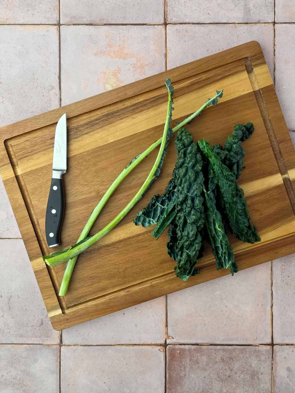 Fresh dinosaur kale leaves on a cutting board with the stems removed, ready to be blended for the chocolate waffles.