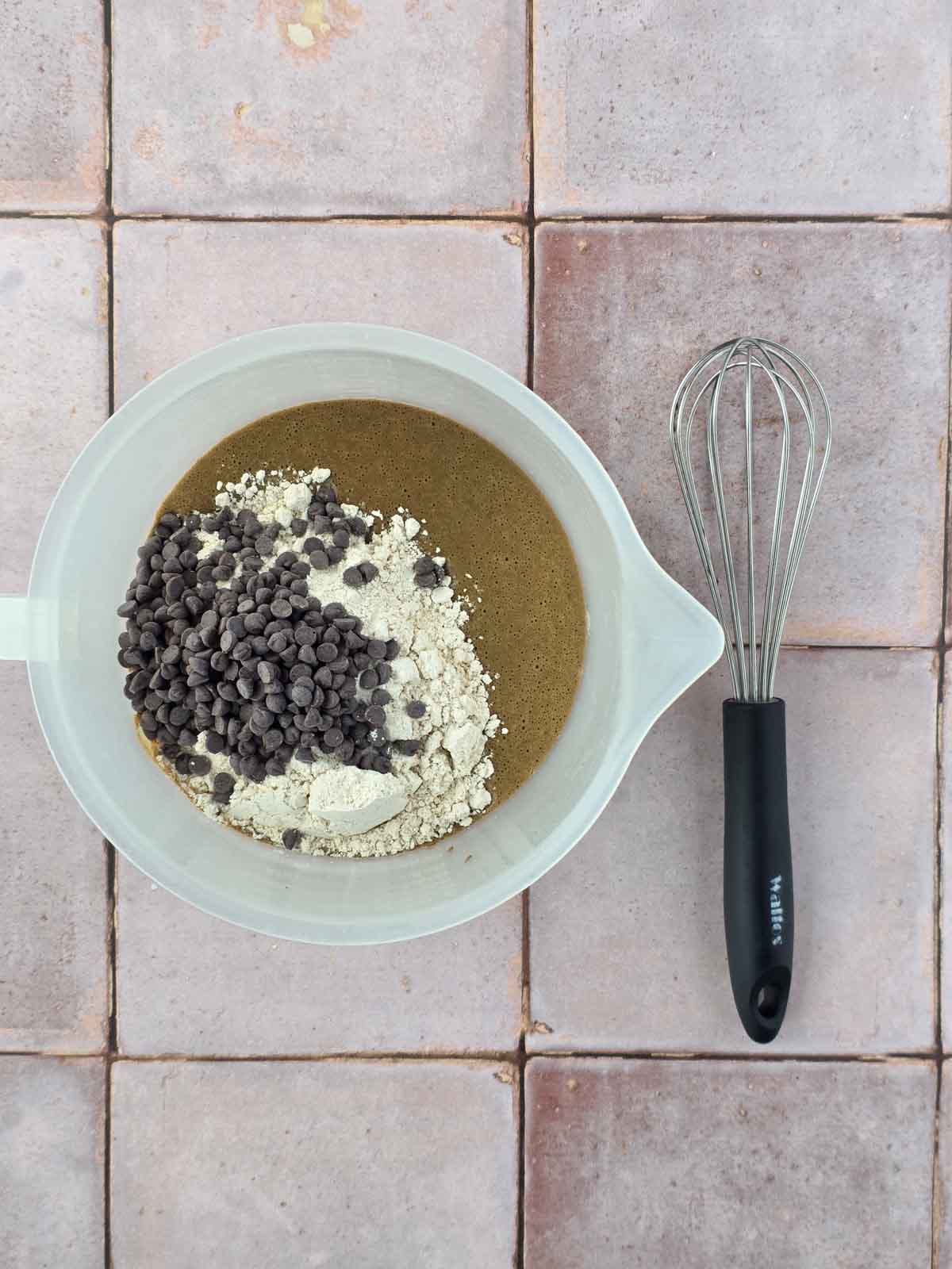 Chocolate waffle batter topped with oat flour and chocolate chips before whisking together.
