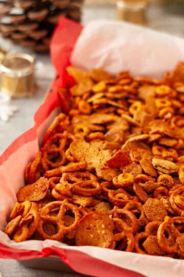 Toasted holiday snack mix piled high with pretzels, cereal squares, and crispy bagel chip pieces.