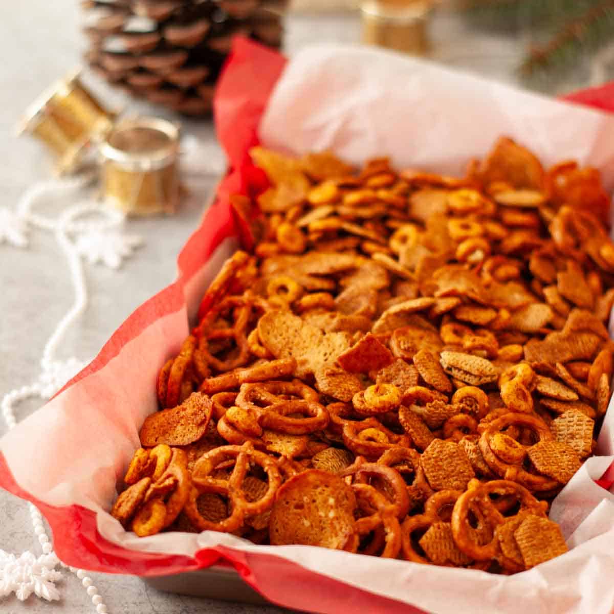 Vegan chex mix piled high with pretzels, cereal squares, and crispy bagel chip pieces.