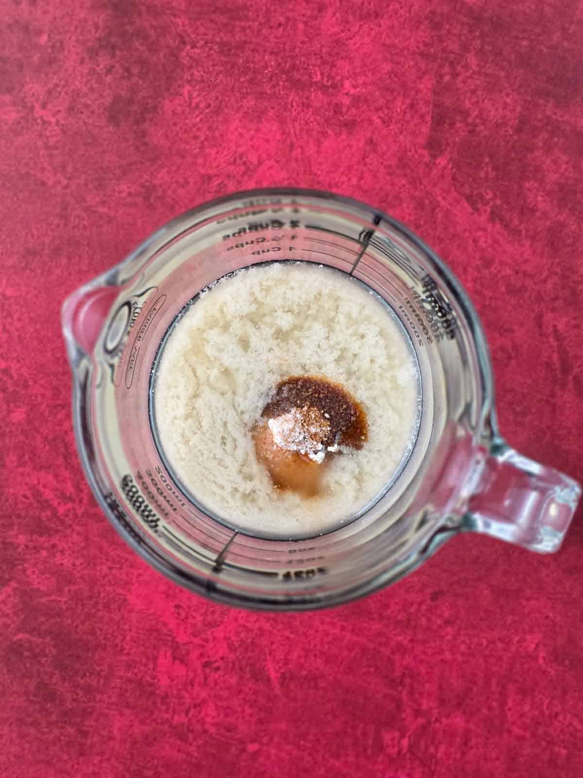 Melted butter in a measuring cup topped with spices and seasonings before mixing.
