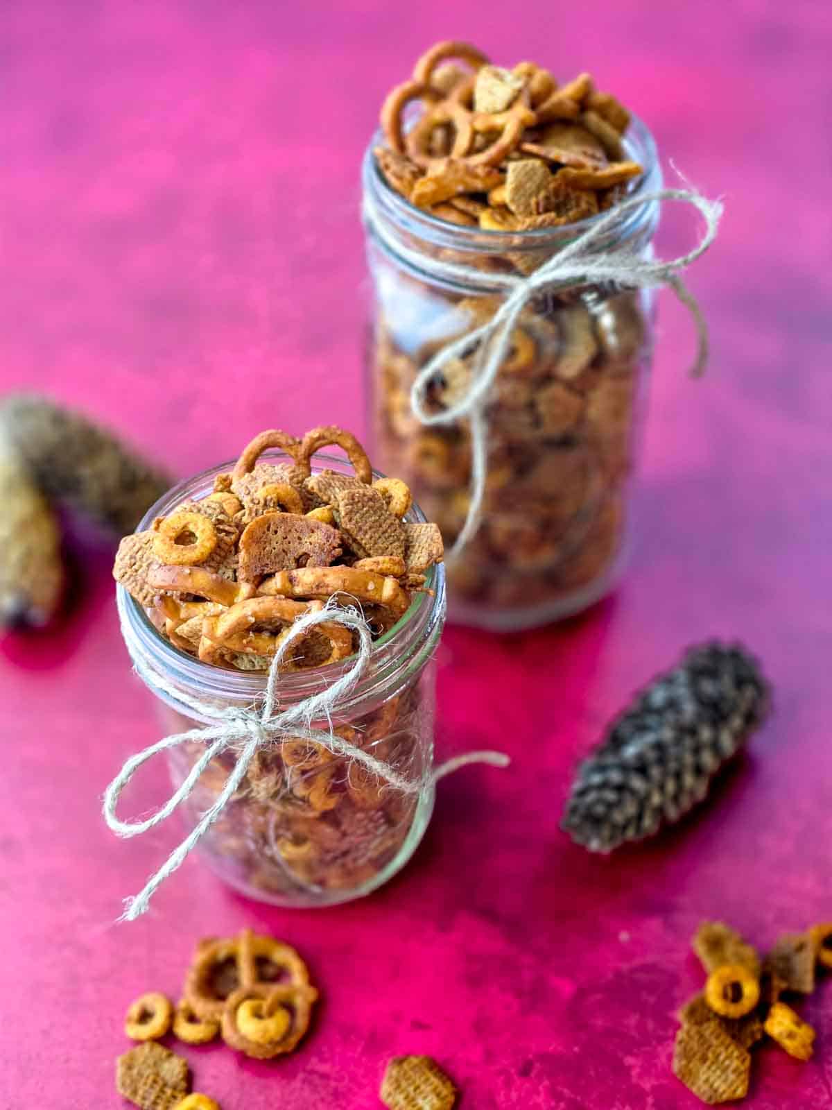 Mason jars filled with vegan chex mix and tied with twine, ready for gifting.