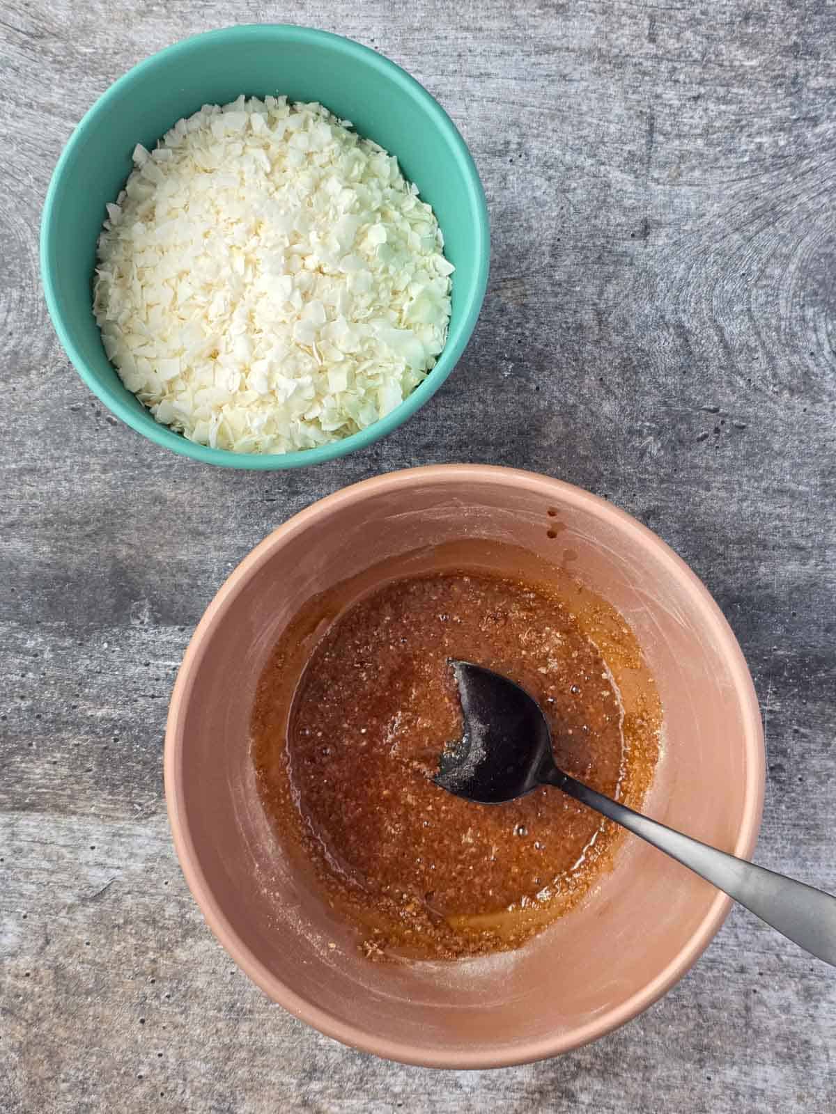 Coconut flakes and a bowl of marinade for coconut bacon bits with a spoon for stirring.