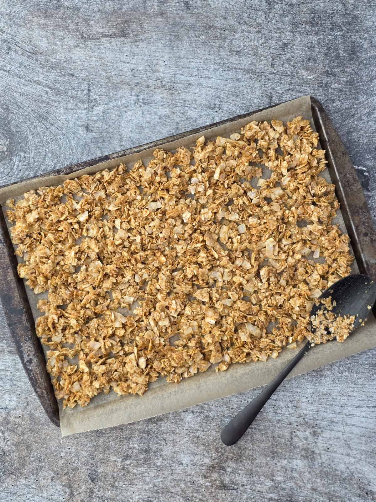Marinated coconut flakes spread on a parchment-lined baking sheet.