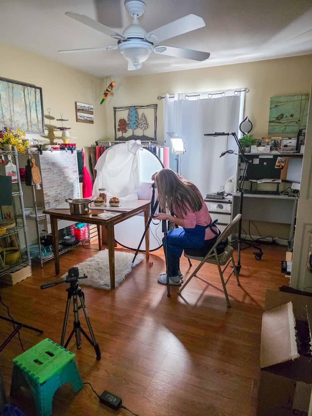 Behind-the-scenes setup for photographing with lights and camera and woman taking a photo.