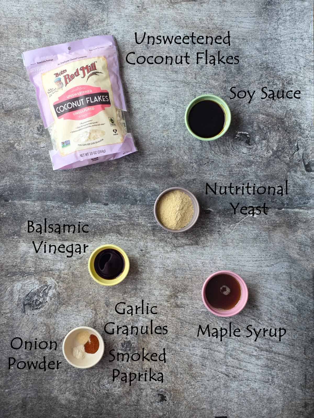 Labeled ingredients in small colored bowls arranged on a gray marbled surface.