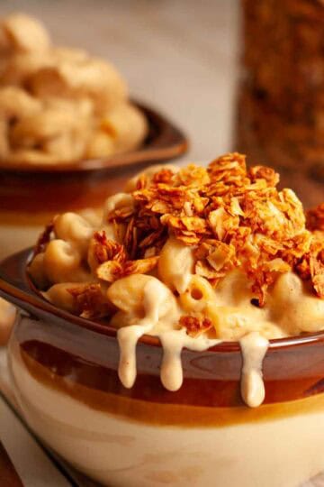 Crispy coconut bacon bits sprinkled over creamy vegan mac and cheese in a cozy ceramic bowl.