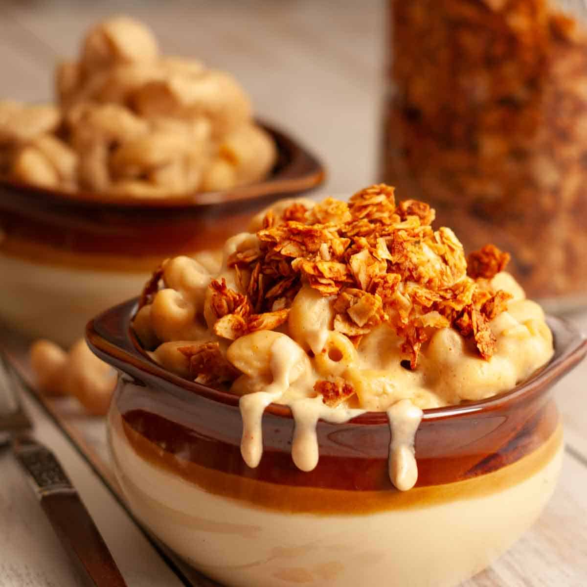 Crispy coconut bacon bits sprinkled over creamy vegan mac and cheese in a cozy ceramic bowl.