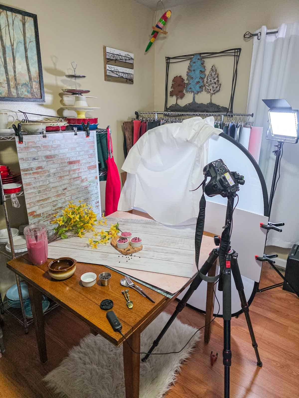 Behind the scenes food photography setup for raspberry pudding with camera, lights, and backdrop.