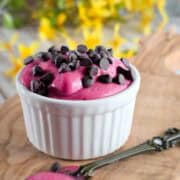 Creamy raspberry pudding served in a white ramekin topped with chocolate chips.