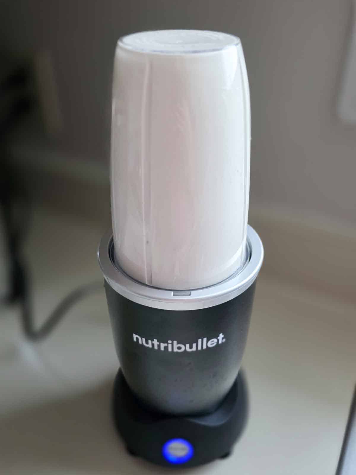 Cashew-and-water mixture blending in a Nutribullet on the kitchen counter.