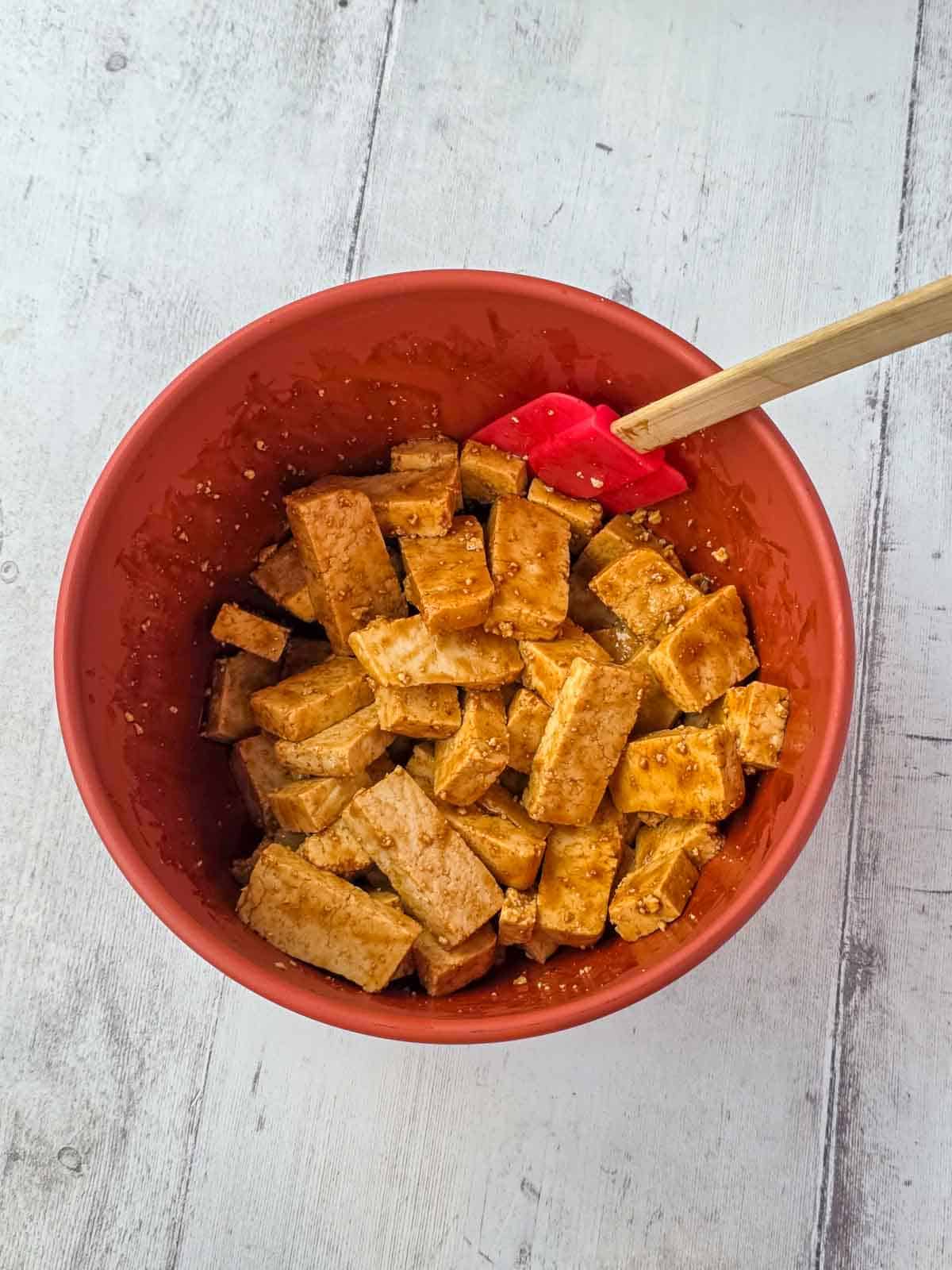 Tofu pieces fully coated is sauce and ready for dry ingredients.