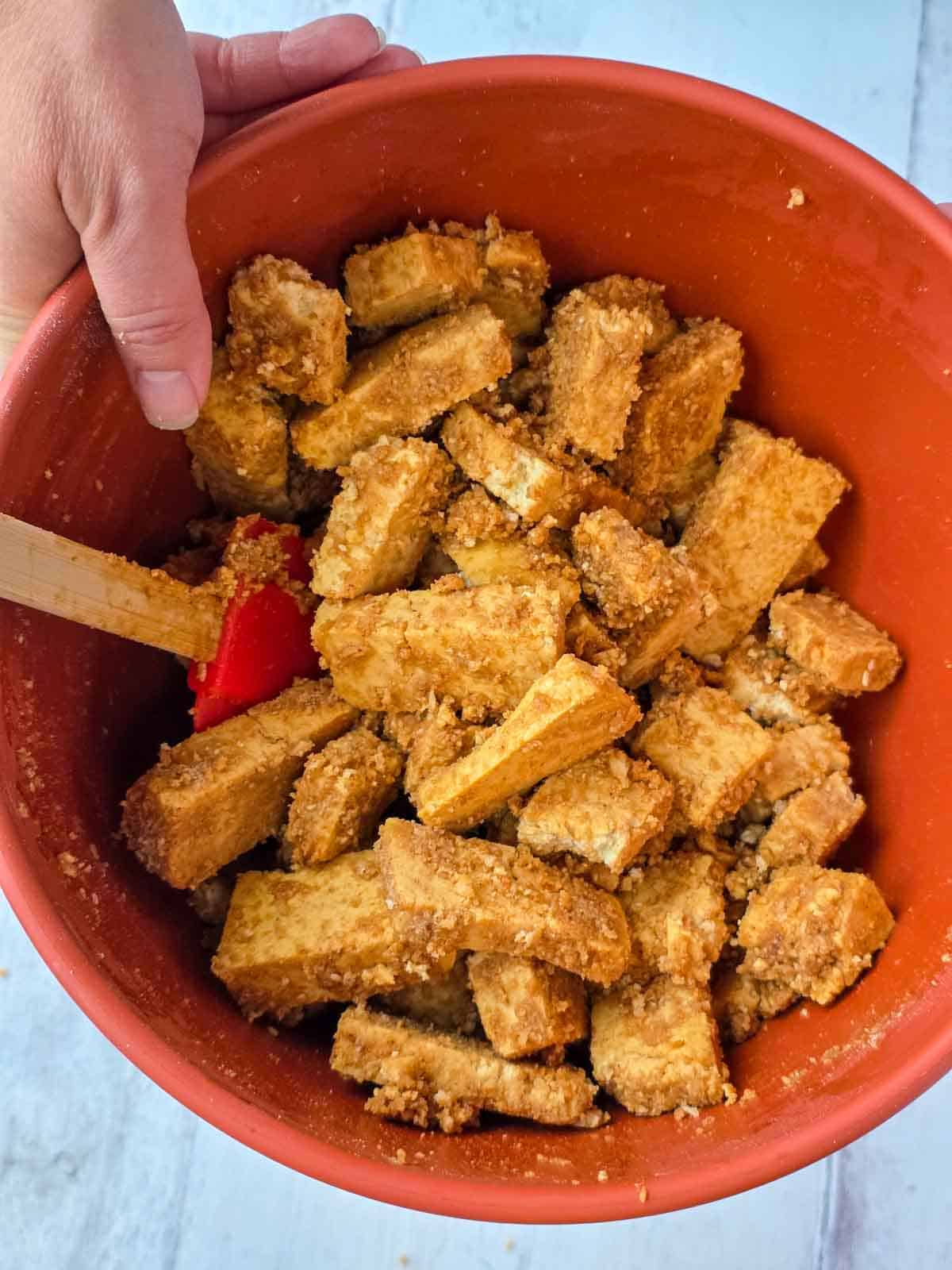 Tofu pieces tossed with breadcrumbs and seasonings until evenly coated.