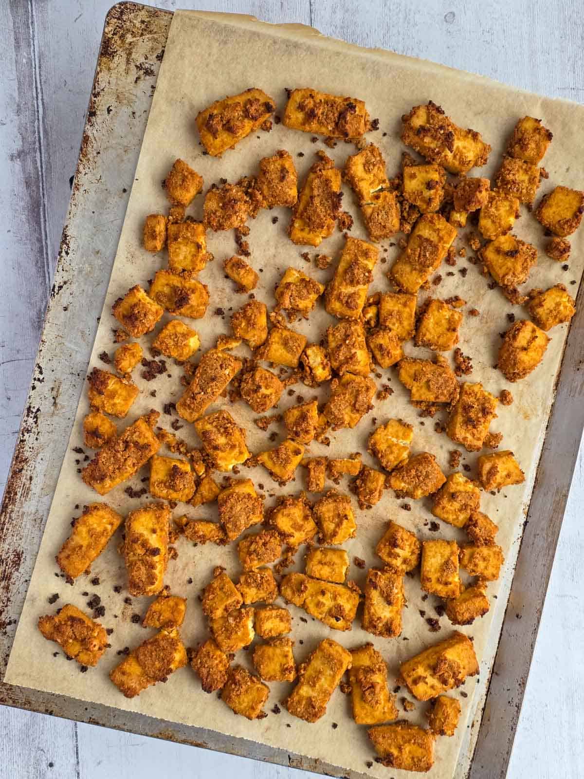 Baked tofu nuggets with a deeply golden, crispy coating fresh from the oven.