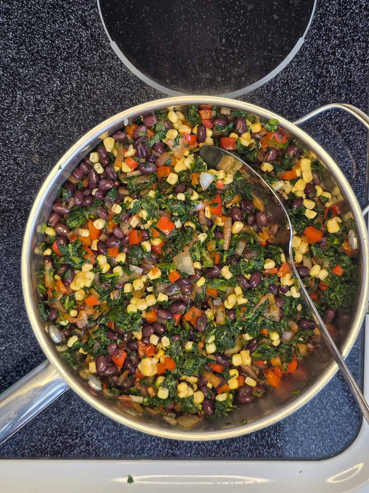 Southwest egg roll filling being stirred with a large spoon in a pan.