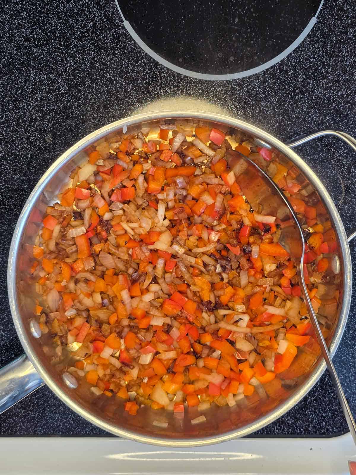 Sautéed onion and bell pepper cooked until softened and lightly caramelized in a skillet.