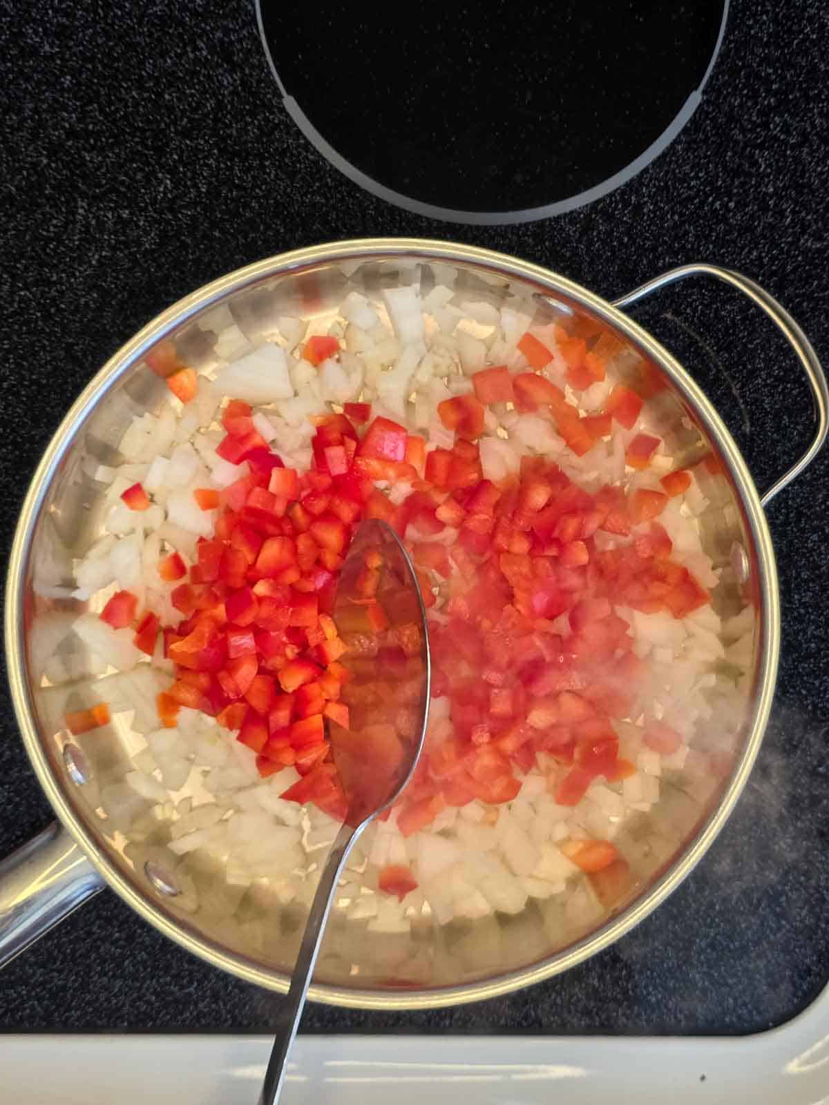 Diced onion and red bell pepper added to a skillet at the start of cooking.