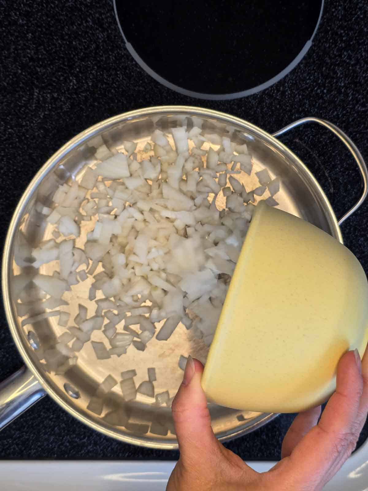 Diced onion added to a skillet to begin sautéing.