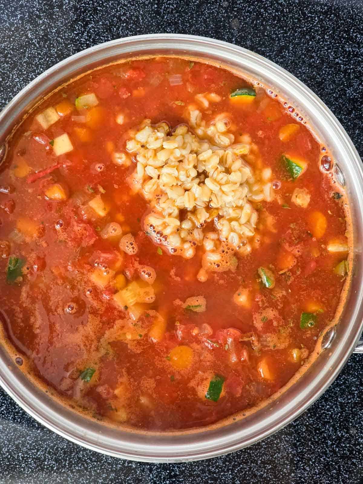 Vegetable barley soup after the barley has been added in, ready to simmer.